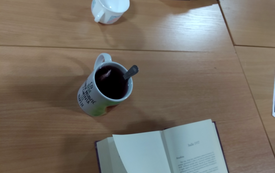 Dwie książki leża otwarte na stole, obok kubki.
