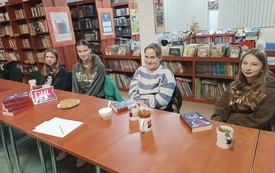 Kilka dziewczyn siedzi przy stole i uśmiech się do osoby robiącej zdjęcie.