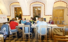 Kilka kobiet siedzi przy stole i rozmawia. 