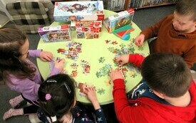 Przy stoliku dzieci układają puzzle