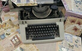 Stara maszyna do pisania stoi na rozrzuconych kolorowych kartkach