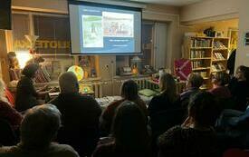 Grupa osób zebranych na spotkaniu w bibliotece.