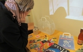 Uczestnicy spotkania przeglądają ułożone na stoliku materiały z czas&oacute;w PRL