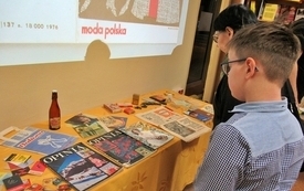 Uczestnicy spotkania przeglądają ułożone na stoliku materiały z czasów PRL