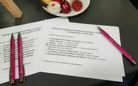 Kartka papieru, długopisu z logo Dyskusyjnych Klubów Książki, talerz.