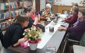Kobiety siedzą przy stole i dyskutują o książkach. 