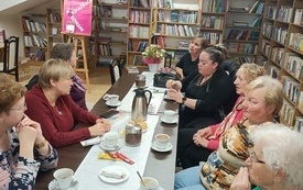 Kilka kobiet dyskutuje przy stole.