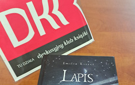 Logotyp DKK i książka &quot;Lapis&quot; leżą na stole. 