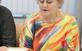 Kobieta siedzi i trzyma książkę.
