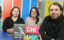 Cztery osoby pozuują do wsp&oacute;lnego zdjecia z logo DKK.