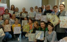Grupa kobiet trzyma albumy wykonane metodą scrapbookingu.