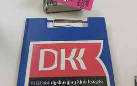 Logo DKK i książka "Miecz przeznaczenia" Andrzeja Sapkowskiego na stoliku.