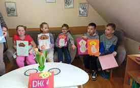 Dzieci siedzą i pozują z książką.