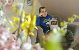 Chłopiec z książka siedzi na fotelu.