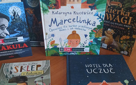 Na stole kilka książek, trzy stoją dwie leżą.