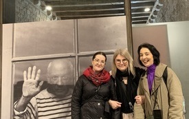 Trzy kobiety pozują do zdjęcia z dużym portretem Pabla Picassa