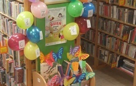 Regalik z książkami dla dzieci przystrojony balonami i motylami z paieru.