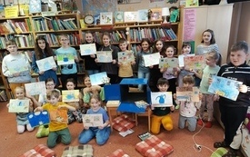 Grupa dzieci pozuje do wsp&oacute;lnej fotografii z wykonanymi przez siebie rysunkami.