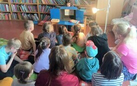 Grupa dzieci ogląda teatrzyk komishibai w bibliotece