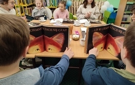 Chłopcy trzymają otwarte książki, pokazują ilustracje lisa.