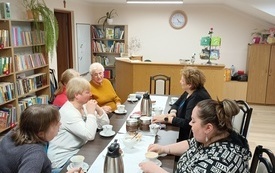 Grupa kobiet siedzi przy stole i rozmawia. 