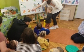 Bibliotekarka wskazuje na tablicy zdjęcia dinozaurów.