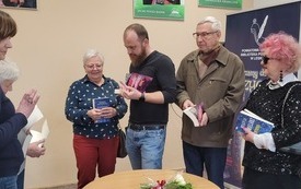 Autor podpisuje książki, wokół niego ludzie.
