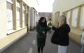 Dziewczyna przekazuje kobiecie idącej ulicą żółty kwiat.