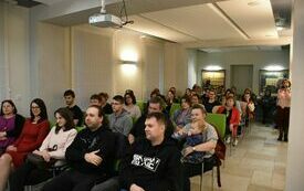 Pełna sala osób siedzących na krzesłach.