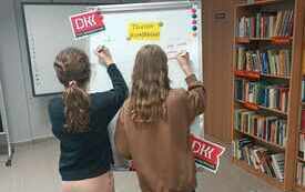 Dwie dziewczynki piszą coś na tablicy. 