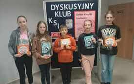 Dzieci pozują do wsp&oacute;lnego zdjęcia, na tle tablicy z logo DKK. 