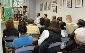 Sala biblioteczna, zebrani uczestnicy spotkania autorskiego. 