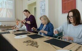 Kobiety przy stole. Wykonują prace plastyczne.