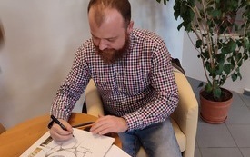 Wojciech Chmielarz podpisuje kronikę biblioteczną. 