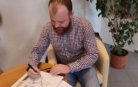 Wojciech Chmielarz podpisuje kronikę biblioteczną.