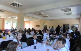 Sala pełna ludzi przy stołach, na których podano jedzenie.