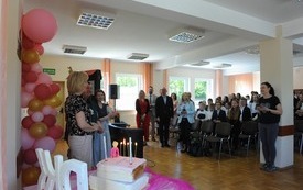 Kilkadziesiąt osób sto i patrzy na tort.