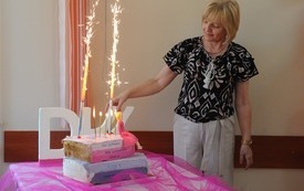 Kobieta stoi, obok na stoliku tort. 