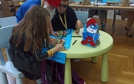 Dzieci w strojach Smerf&oacute;w siedzą przy stoliku z kartą konkursową