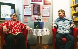 Kobieta i mężczyzna w średnim wieku rozmawiają siedząc w czerwonych fotelach