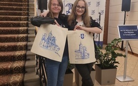 Dwie młode kobiety pozują do zdjęcia prezentując wykonane na warsztatach w bibliotece torby na zakupy