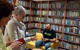 Mężczyzna podpisuje książki, w tle kolejka po autograf.