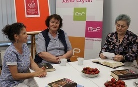 Kilka osób pozuje do wspólnego zdjęcia, siedząc przy stole.
