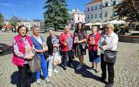 Grupa kobiet trzyma książki i stoi w p&oacute;łkolu na jednej z ulic Krosna. 