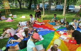 Grupa dzieci czyta książki leżąc na trawie