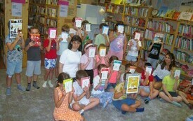 Grupa dzieci pozuje do zdjęcia siedząc w bibliotece na podłodze i trzymając książki