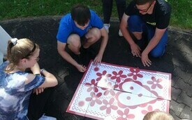 Młodzi ludzie układają wielkoformatowe puzzle z motywem lasowiackiego serca