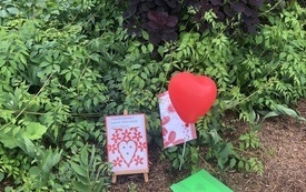 Czerwony balon w kształcie serca i tabliczki do gry ustawione na ziemi