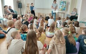 Mężczyzna pokazuje zgormadzonej publiczności książkę.