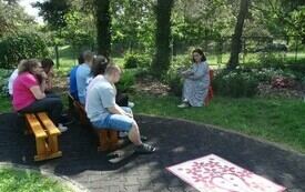 Bibliotekarka czyta dzieciom siedzącym w parku